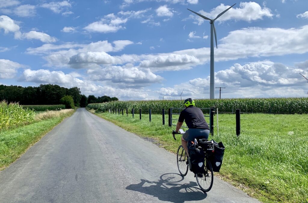 David auf dem Fahrrad auf einer Landstraße in Ochtrup mit Windkraftrad im Hintergrund