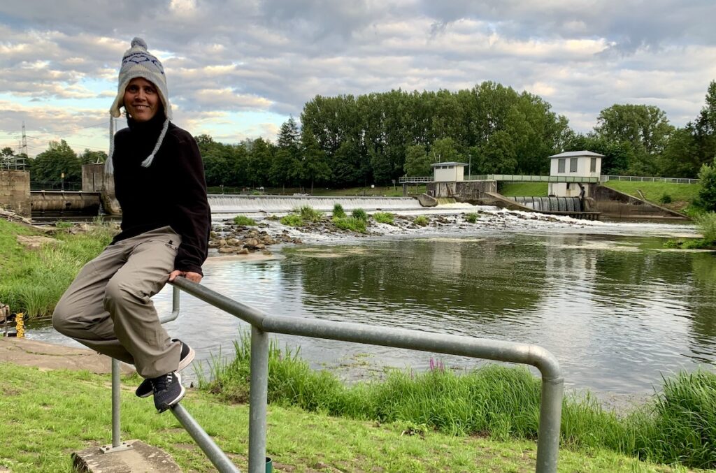 Ich sitze auf einem Geländer vor dem Fluß Ems in der Nähe des Campingplatz am Waldsee in Lingen