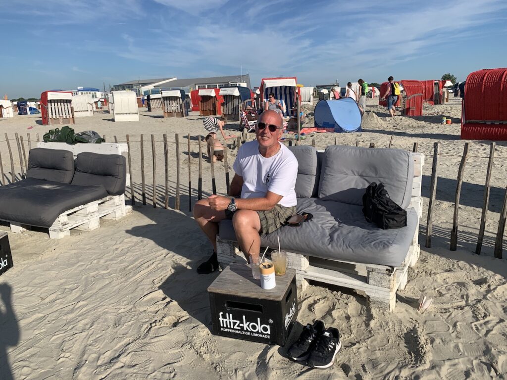 David mit Cocktails auf einer Bank aus Europaletten an der Strandbar in Bensersiel